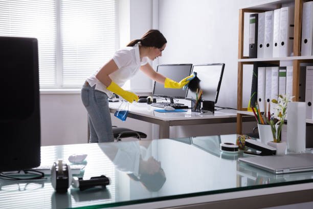 young woman cleaning computer with rag in office young woman cleaning computer with rag in office
